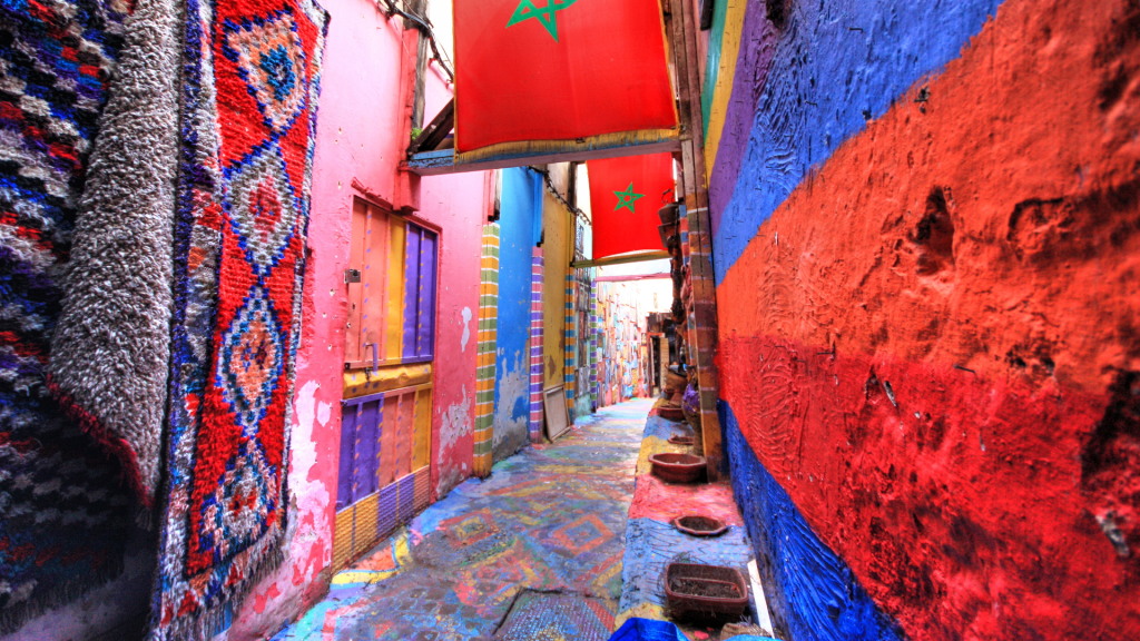 A vibrant, colorful alleyway lined with carpets and other goods in Fes, Morocco